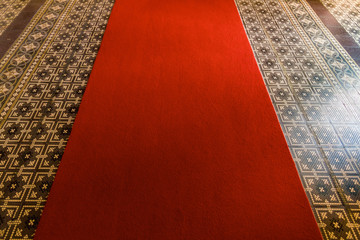 Red entrance carpet on ancient mosaics in a hallway