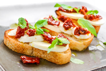 Tasty savory Italian appetizers, or bruschetta, on slices of toasted baguette garnished with basil