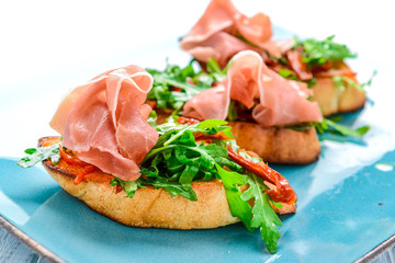 Tasty savory Italian appetizers, or bruschetta, on slices of toasted baguette garnished with basil