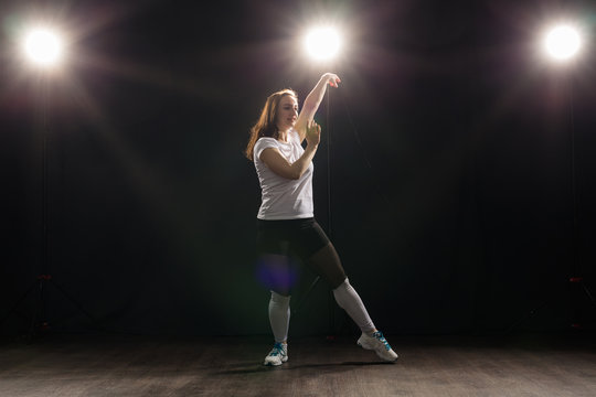 People and dance concept - Young woman dancing jazz funk over dark background