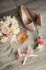 bridal accessories such as shoes, earrings, bouquet and perfume lie on a table