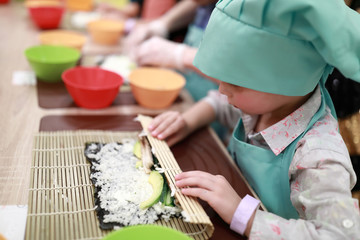 Child rolling mat over sushi © Arkady Chubykin