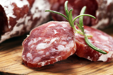 thinly sliced salami on a wooden texture on the background.