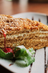 a piece of poured honey cake with chocolate topping on a plate, side view