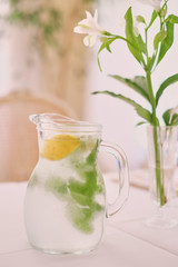Glass jug of cold lemonade on a light background cafe. Pitcher lemon water with mint. Cold lemonade box