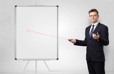 Young businessman with laser pointer and copyspace white blackboard