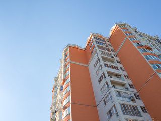 Colored facade wall of a modern residential building with a view from the bottom up against the sky.
