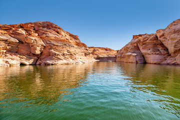 Fototapeta na wymiar Glen Canyon coloured sandstone cliffs filled with water, near Lake Powell and the Colorado River, straddling the border between Utah and Arizona. National park and popular tourist attraction
