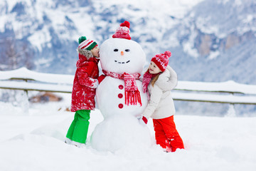 Child building snowman. Kids build snow man.