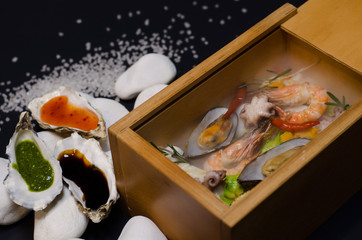seafood in a wooden box with white stones