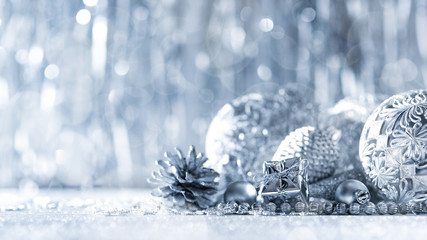 Shiny silver christmas present and beautiful ornaments, with defocused christmas lights in the background. Christmas banner.