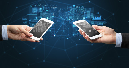 Close up of two hands holding smartphones to sync business data