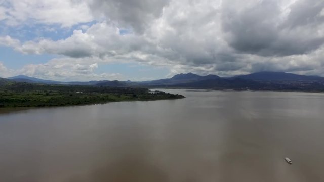 Aerial drone shot above a mountain lake with a boat on the water moving