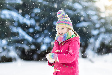 Child playing with snow in winter. Kids outdoors.