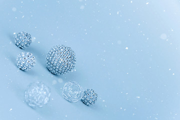 Silver shiny Christmas bauble decoration on pastel blue background.