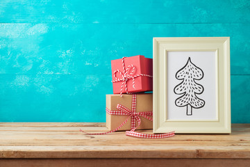 Christmas holiday background with pine tree drawing and gift boxes on wooden table