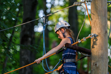 ortrait of cute little  girl walk on a rope bridge in an adventure rope park.