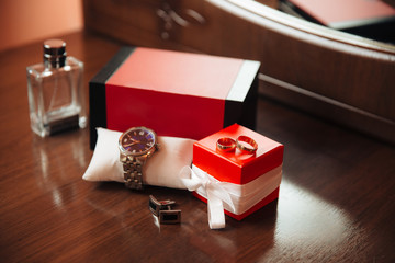 Men's watches, perfume, wristwatches, golden rings and cufflinks on the background of a brown...
