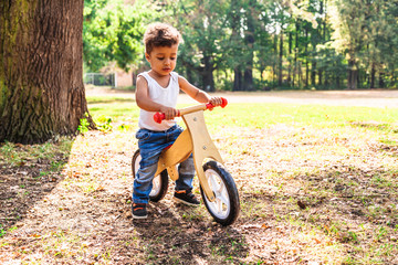 Afro-american or latin little boy ride bicycle in park