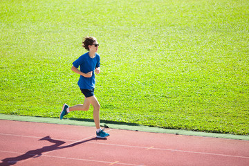 Teenager boy running on race track. Kids run.