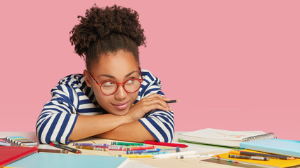 Dreamy black artisitc director looks pensively aside, leans at hands, thinks about new ideas for...