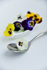 Edible flowers - Pansy, spoon with flowers on white . the concept of healthy eating, vegetarian and natural food.