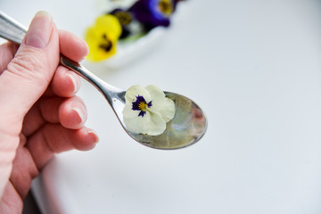 Edible flowers - Pansy, spoon with flowers on white . the concept of healthy eating, vegetarian and natural food.