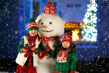 Kids and snowman in garden at Christmas fireplace.