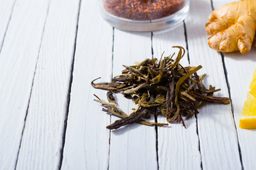 cup of tea, different leaves, honey, lemon ginger and brown sugar on white wooden table background