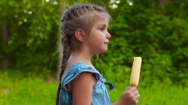 Cute girl eating popsicle ice-cream in park