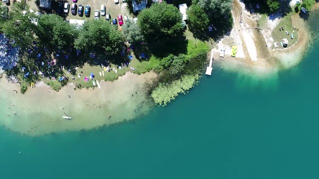 Aerial top view of people sunbathing swimming  relaxing  and jumping in lake