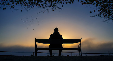 man on bench with sunrise
