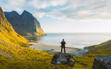  Adventurous man standing on a rock.Beautiful view of Lofoten High quality beach and an amazing...