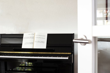 Fototapeta na wymiar a black piano in a modern white living room with music sheets
