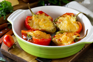 Stuffed peppers with turkey meat and cheese on a wooden table. Healthy food, close-up.