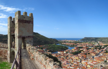 One of the seven towers of the Serravalle caste looking out over the winding river and the old village of Bosa with colourful houses and red roofs, Sardinia, Italy