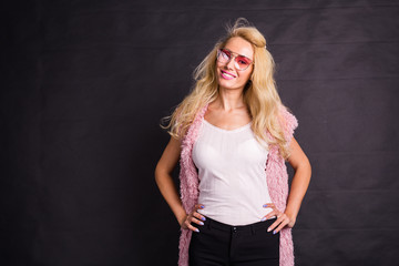 Fashion and beauty concept - Beautiful blond woman dressed in white shirt and pink cardigan over dark background with copy space