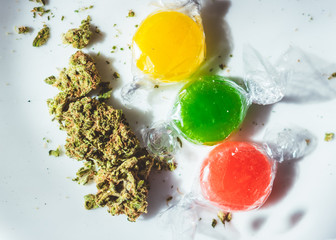 Medicated hard candies with marijuana buds on white background