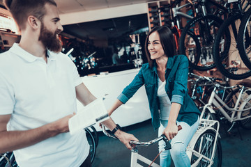 Girl Chooses City Bike with Seller in Sport Store
