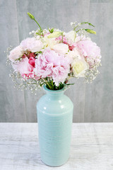 Pink bouquet of peonies and roses in wooden box.