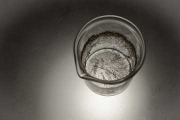 Chemical glass with crystals of salicylic acid on a matte glass