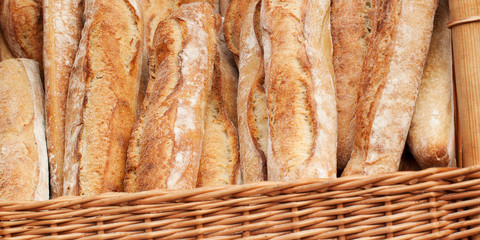 several fresh white baguettes in a basket on the counter in a store or on the market
