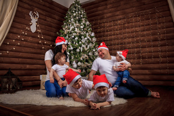 A large happy family gathered at home under the Christmas tree. Same outfits for the whole family. Festive mood. New Year's and Christmas. Big family.