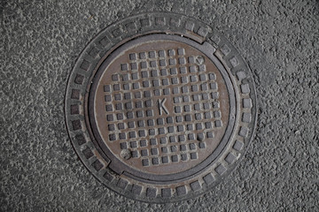 Manhole cover in the road of asphalt