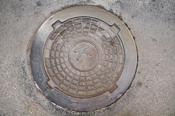 Manhole cover in the road of asphalt