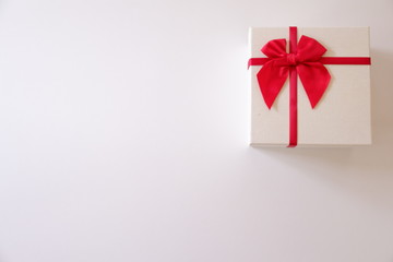 Close-up  white gift box with red ribbon on white background.