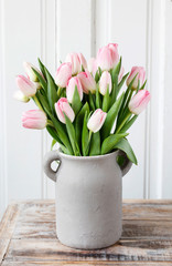 Bouquet of pink tulips in grey ceramic vase.