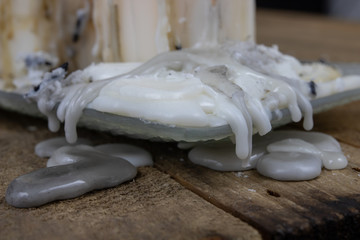 Old candles with dirty wax on a wooden table. Burning dirty candlesticks on a glass stand.
