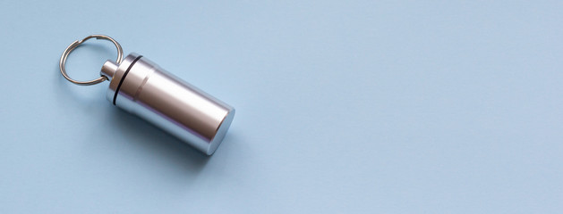 Metal container for pills on a blue background, close-up