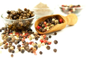 Pepper in wooden spoon. Mix of different peppers balls on white background. Sale of spices.